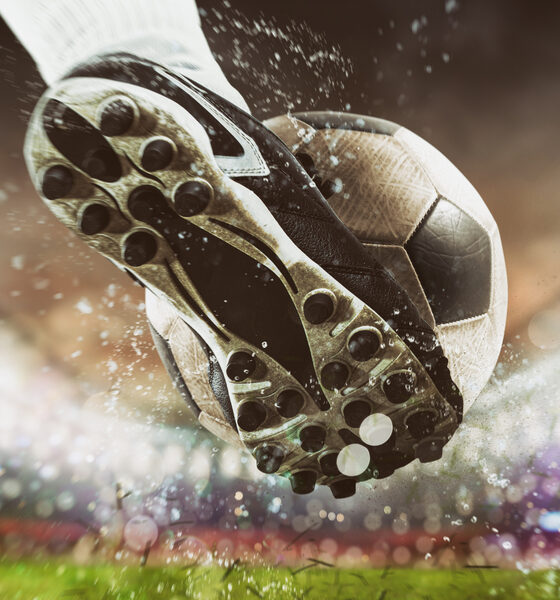 Soccer player kicks the ball vigorously at the stadium